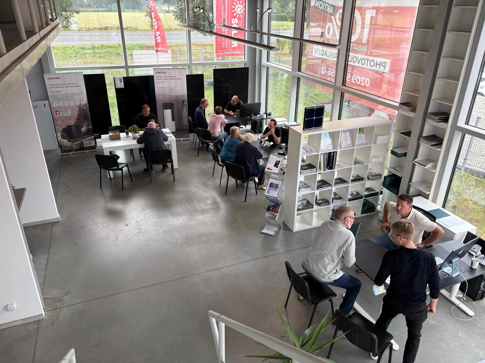 Mauro-Solar-Ausstellung mit Besuchern an mehreren Beratungstischen und ausgestellten Solarmodulen.