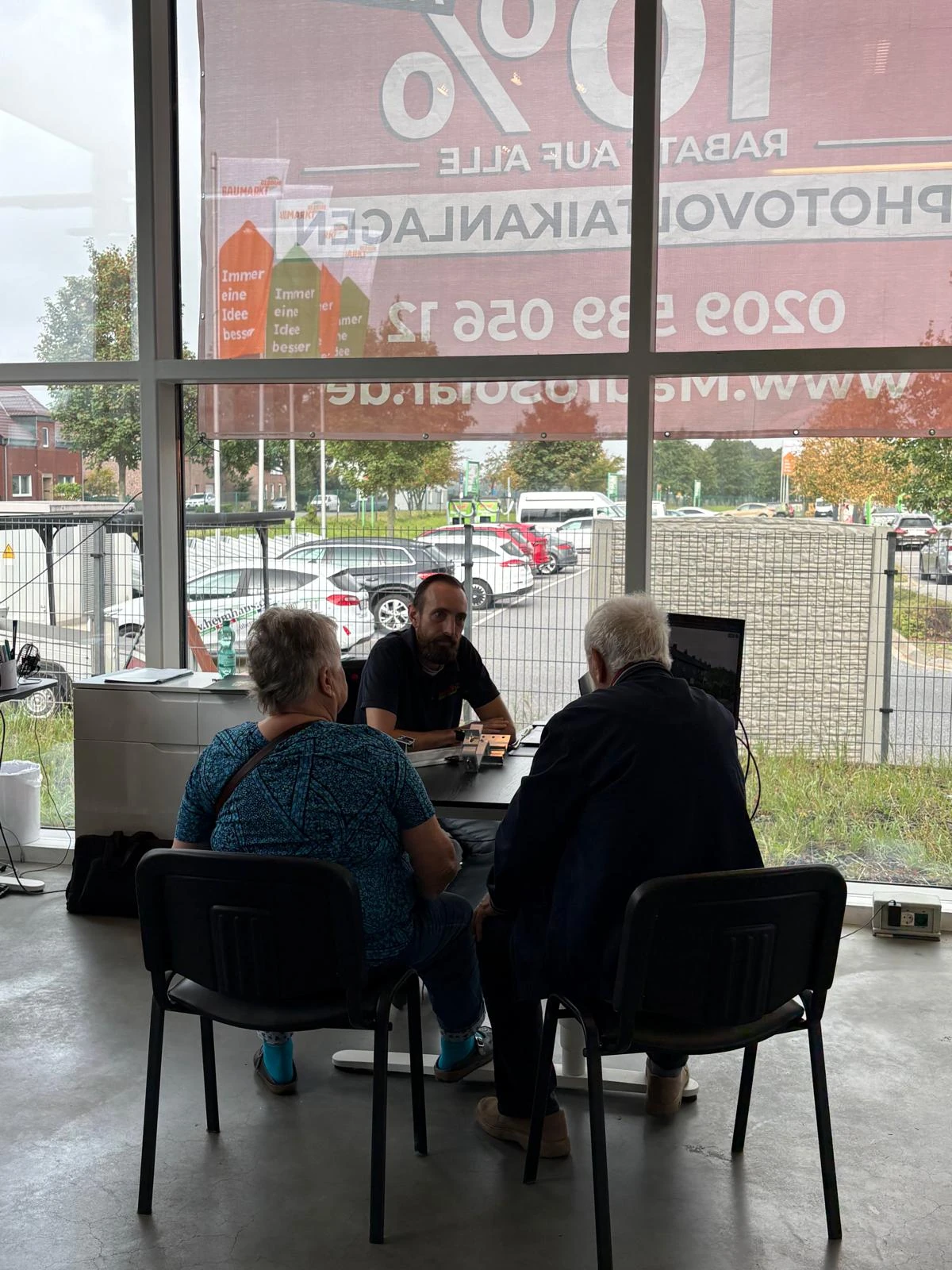 Zwei Besucher im Beratungsgespräch an einem Schreibtisch bei Mauro Solar.