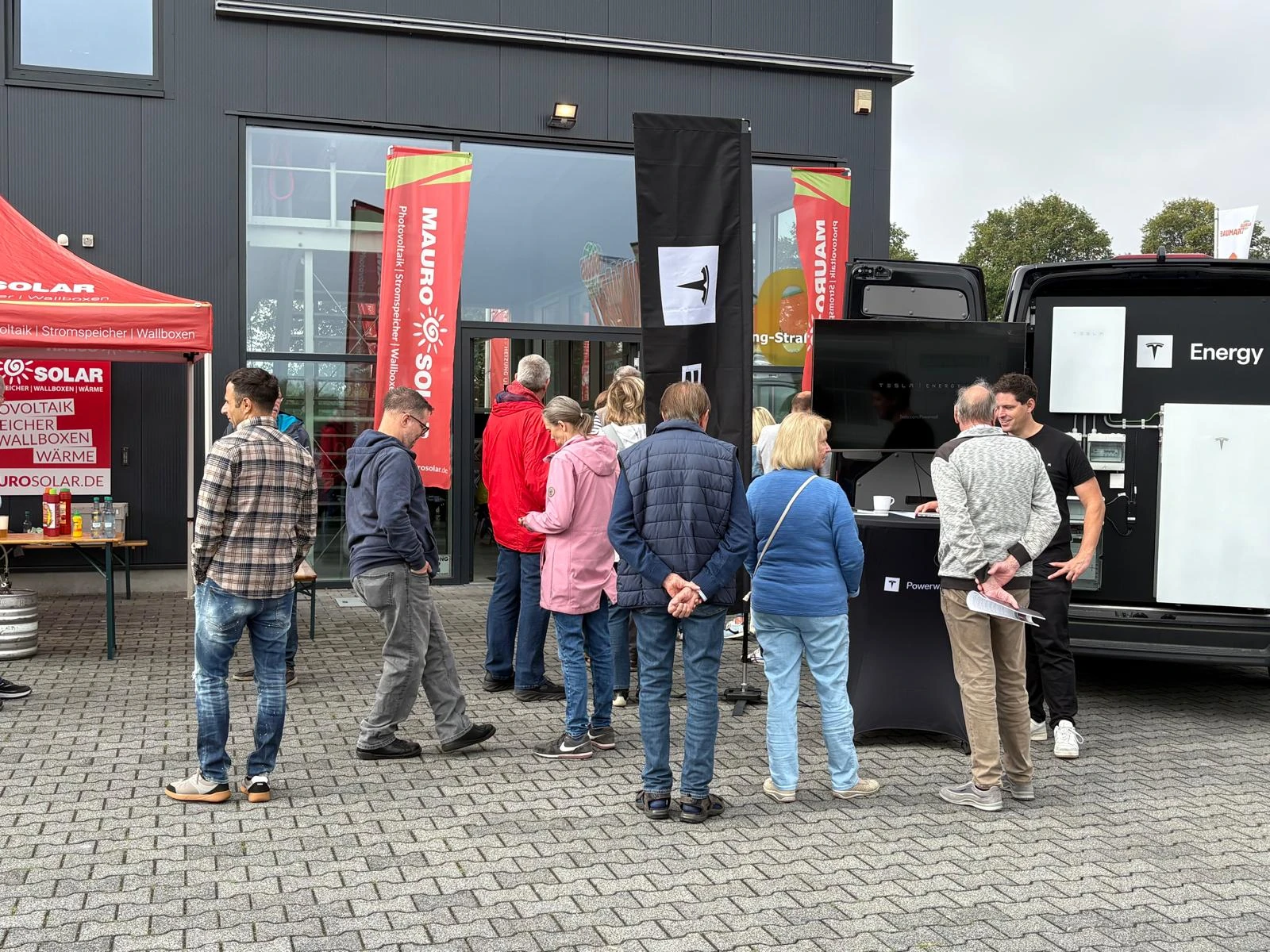 Besucher am Tesla-Energy-Stand mit ausgestellten Stromspeichern bei Mauro Solar.