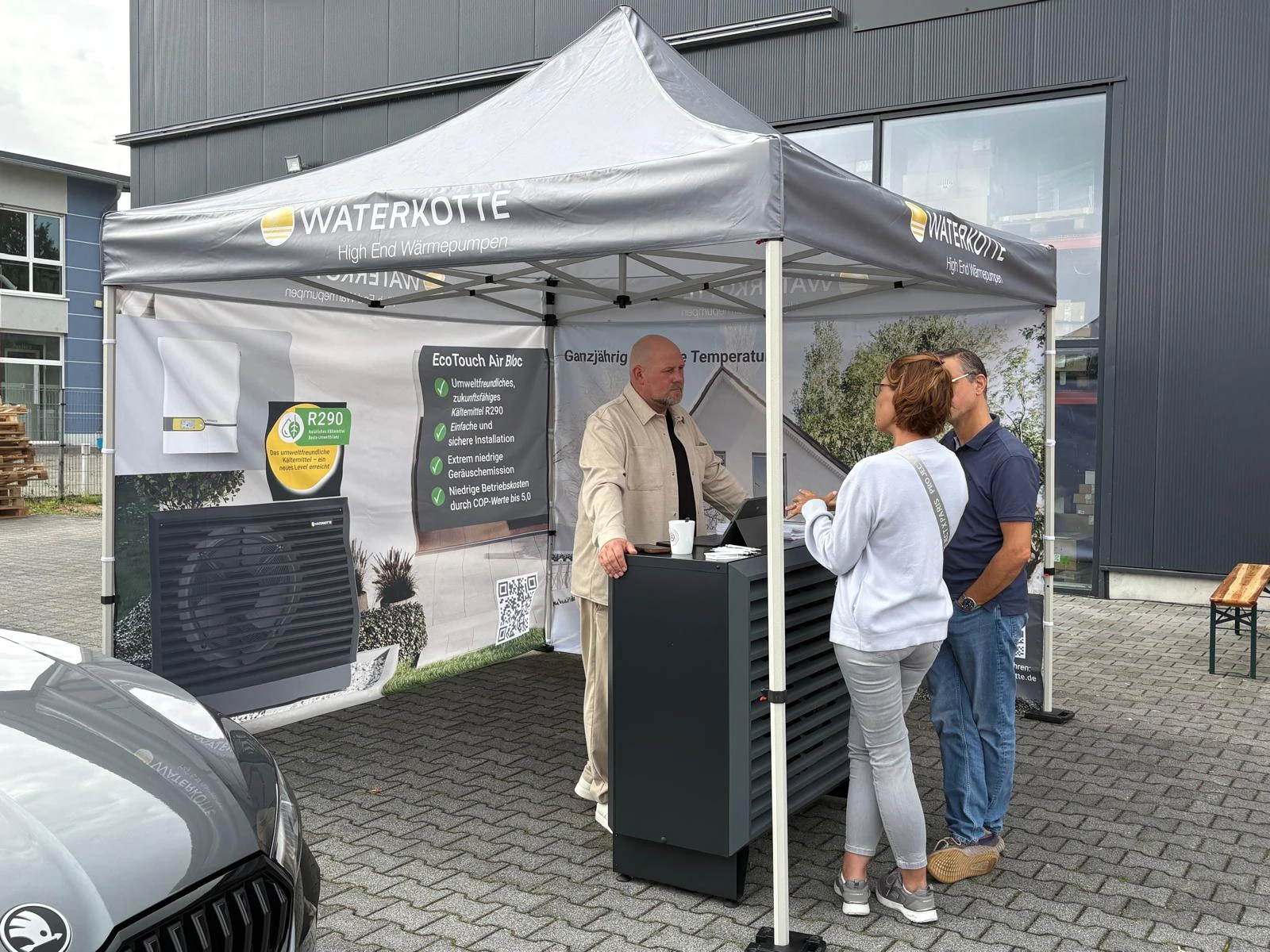 Besucher im Gespräch am WATERKOTTE-Stand neben einer ausgestellten Wärmepumpe.